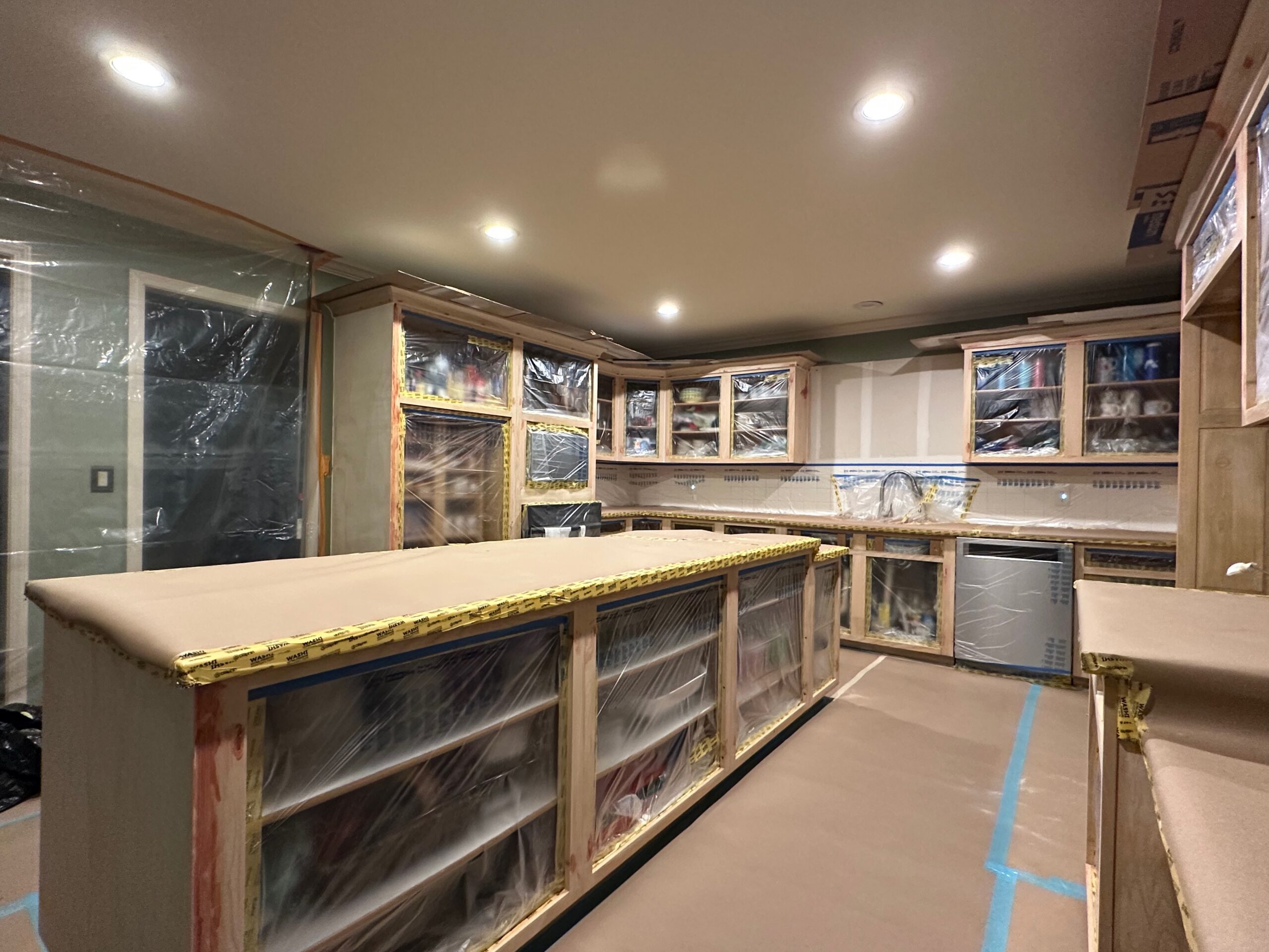Kitchen cabinets fully masked and protected before cabinet painting and refinishing