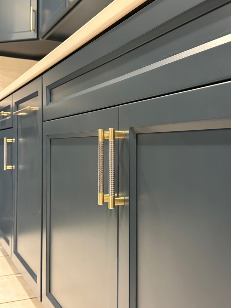 Close-up of blue painted cabinet doors with brushed gold handles